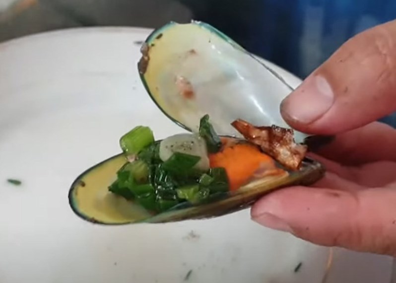adding spring onion oil onto a green mussel